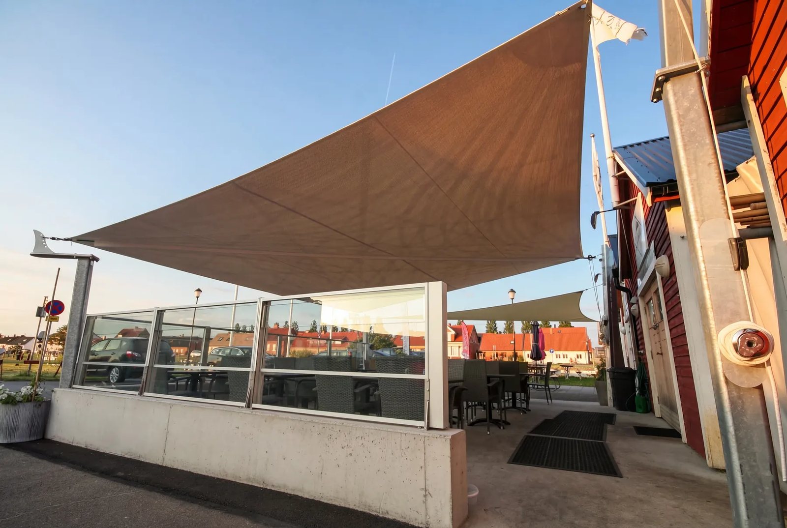 Mörk segelduk spänd över pool med svarta loungemöbler